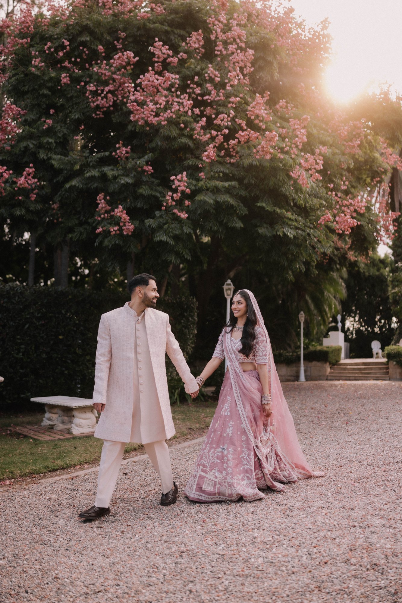Newlyweds walking together through a sunlit garden