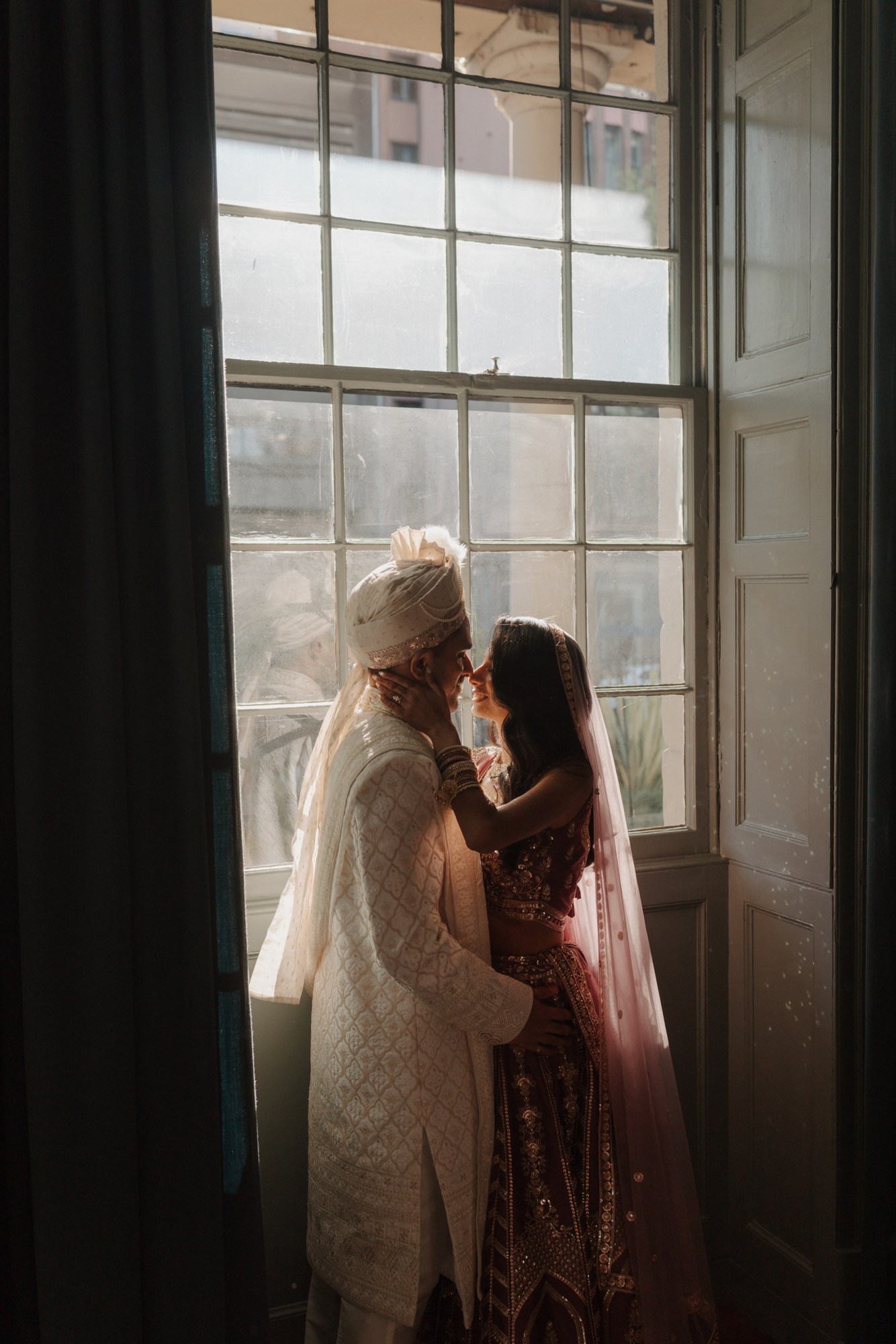Newlyweds sharing a quiet embrace in soft window light